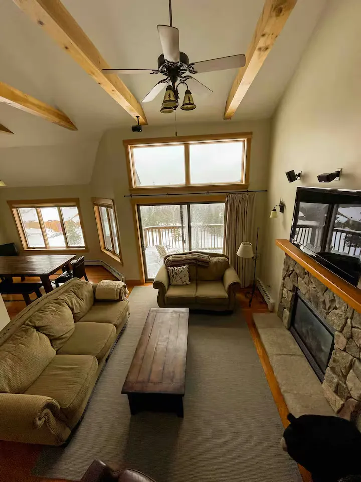 A living room with couches, a coffee table, a ceiling fan, and a fireplace.